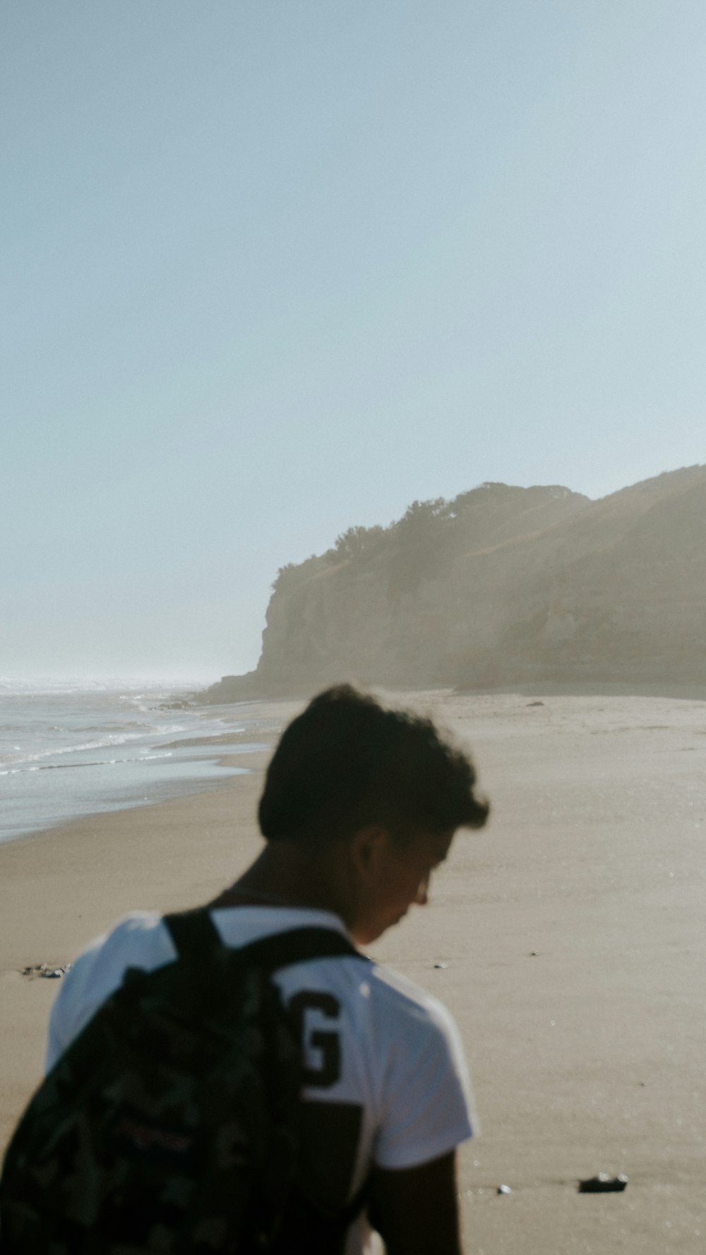 a man standing on top of a beach next to the ocean