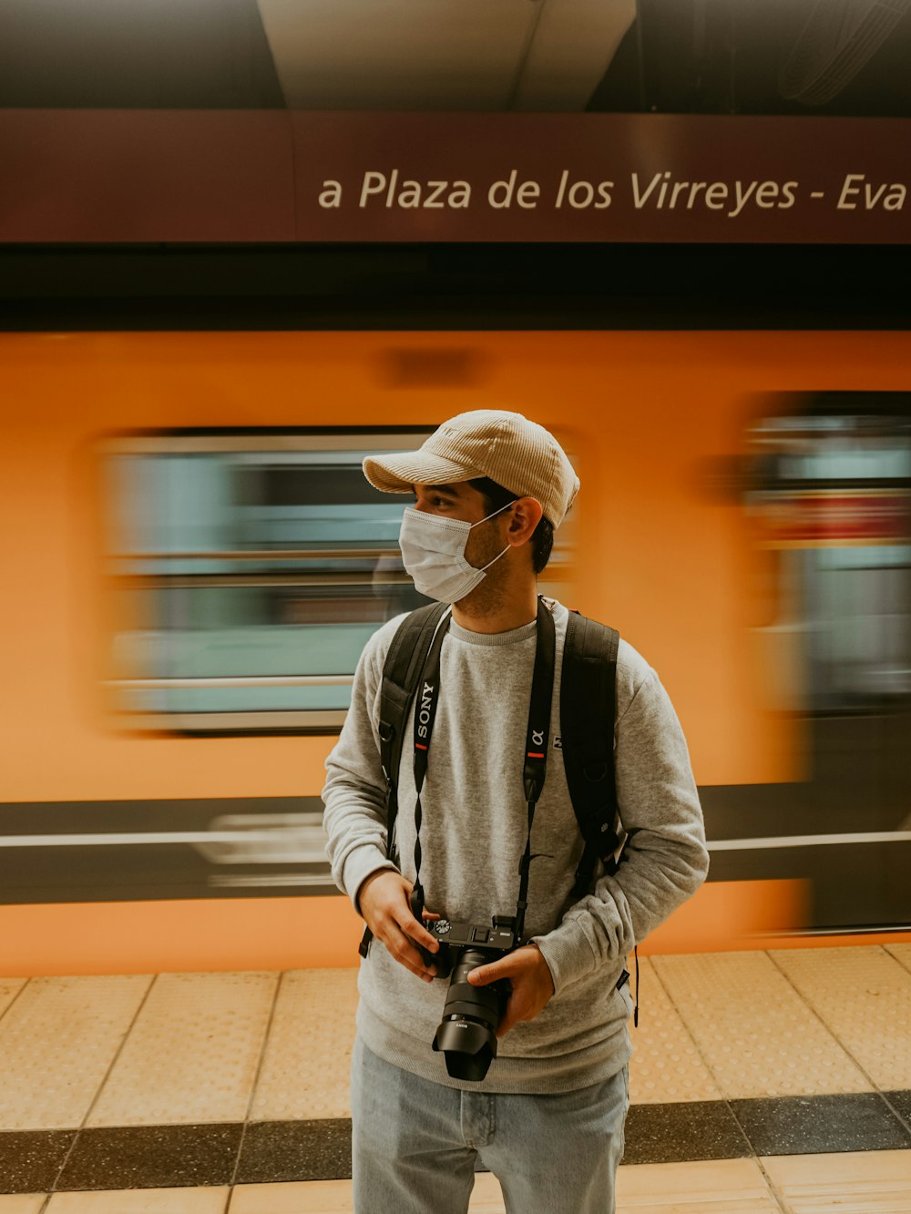 a man wearing a face mask standing in front of a train