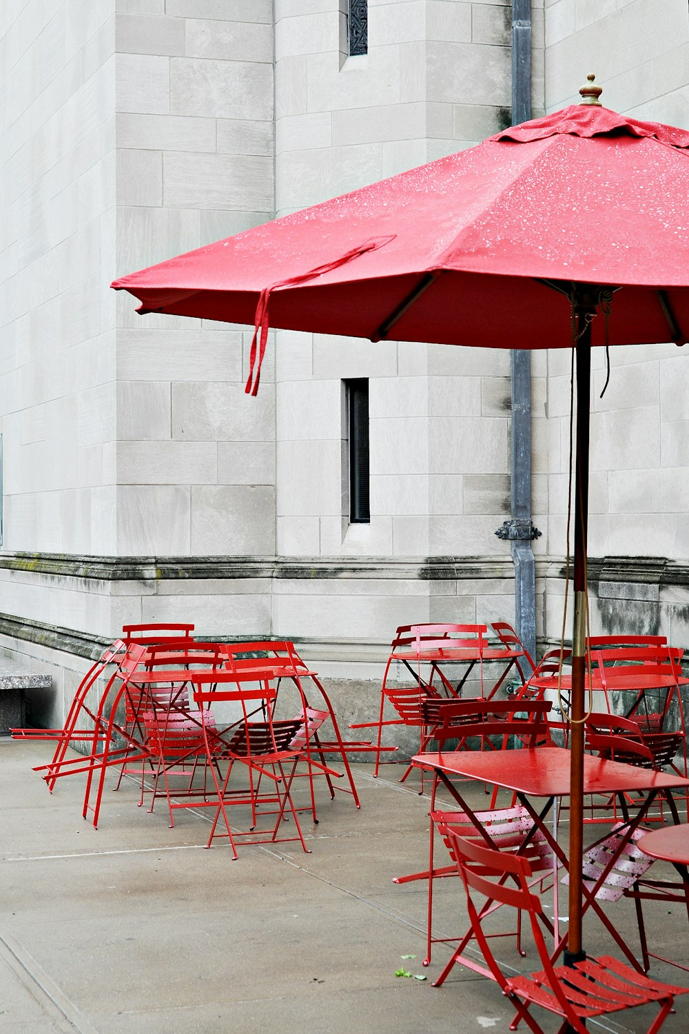 a bunch of red tables and chairs with a red umbrella