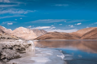 a body of water surrounded by mountains under a blue sky