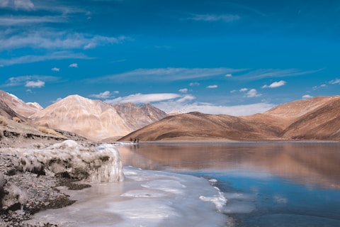 a body of water surrounded by mountains under a blue sky