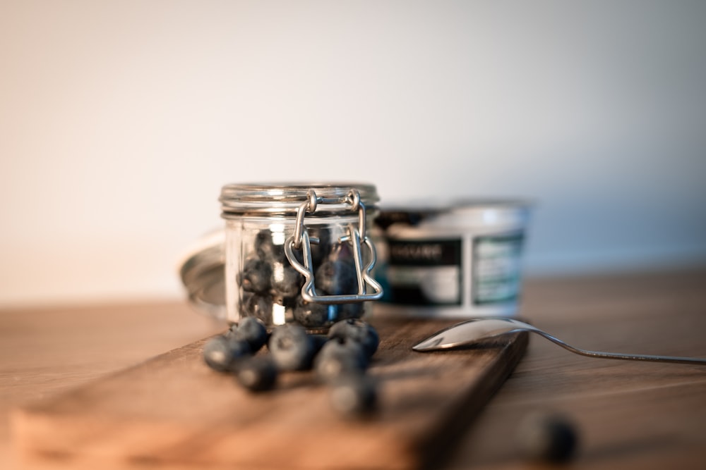 a wooden cutting board topped with a jar of blueberries