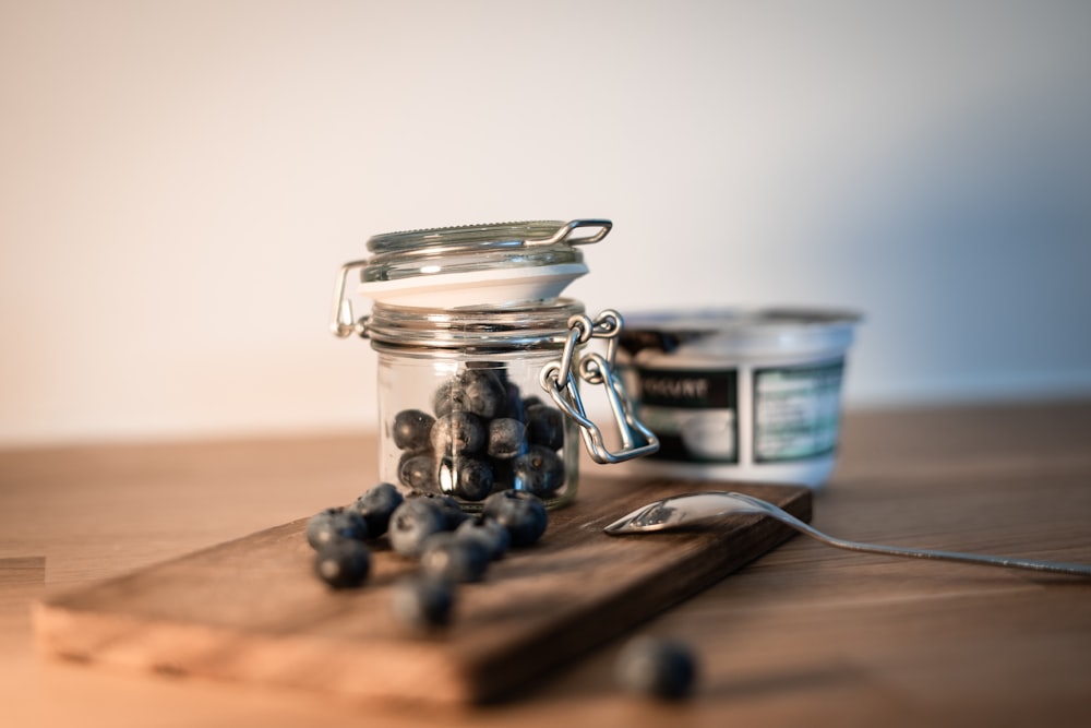 a wooden cutting board topped with a jar of blueberries