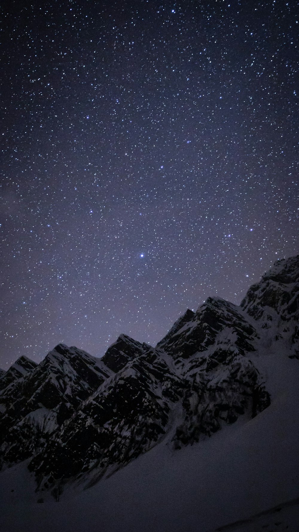 the night sky over a snowy mountain range