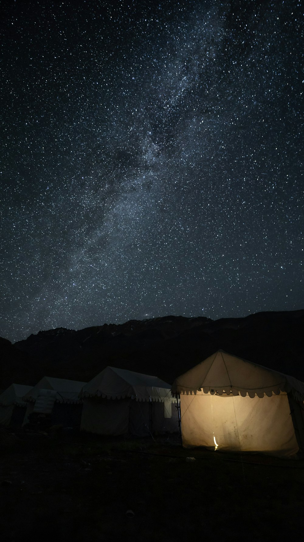 a group of tents under a night sky filled with stars