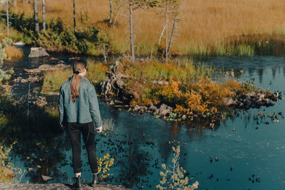 a woman standing on a rock looking at the water