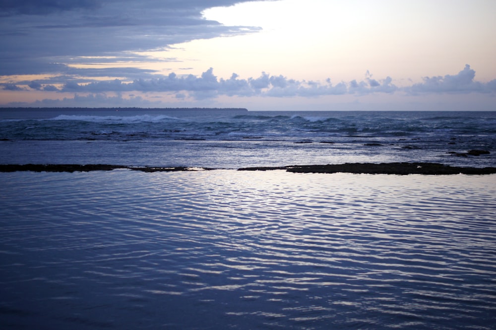 a body of water with a sky in the background