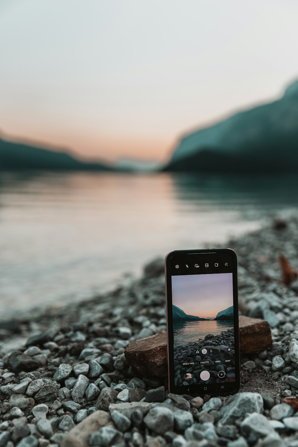 a cell phone sitting on top of a rocky beach
