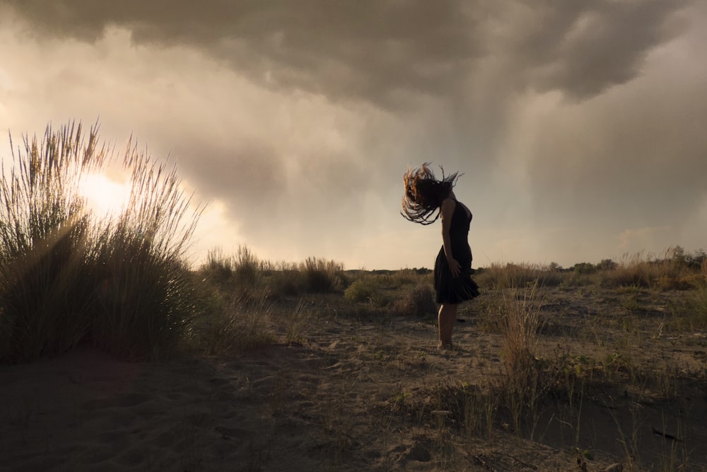 a woman standing in a field with her hair blowing in the wind