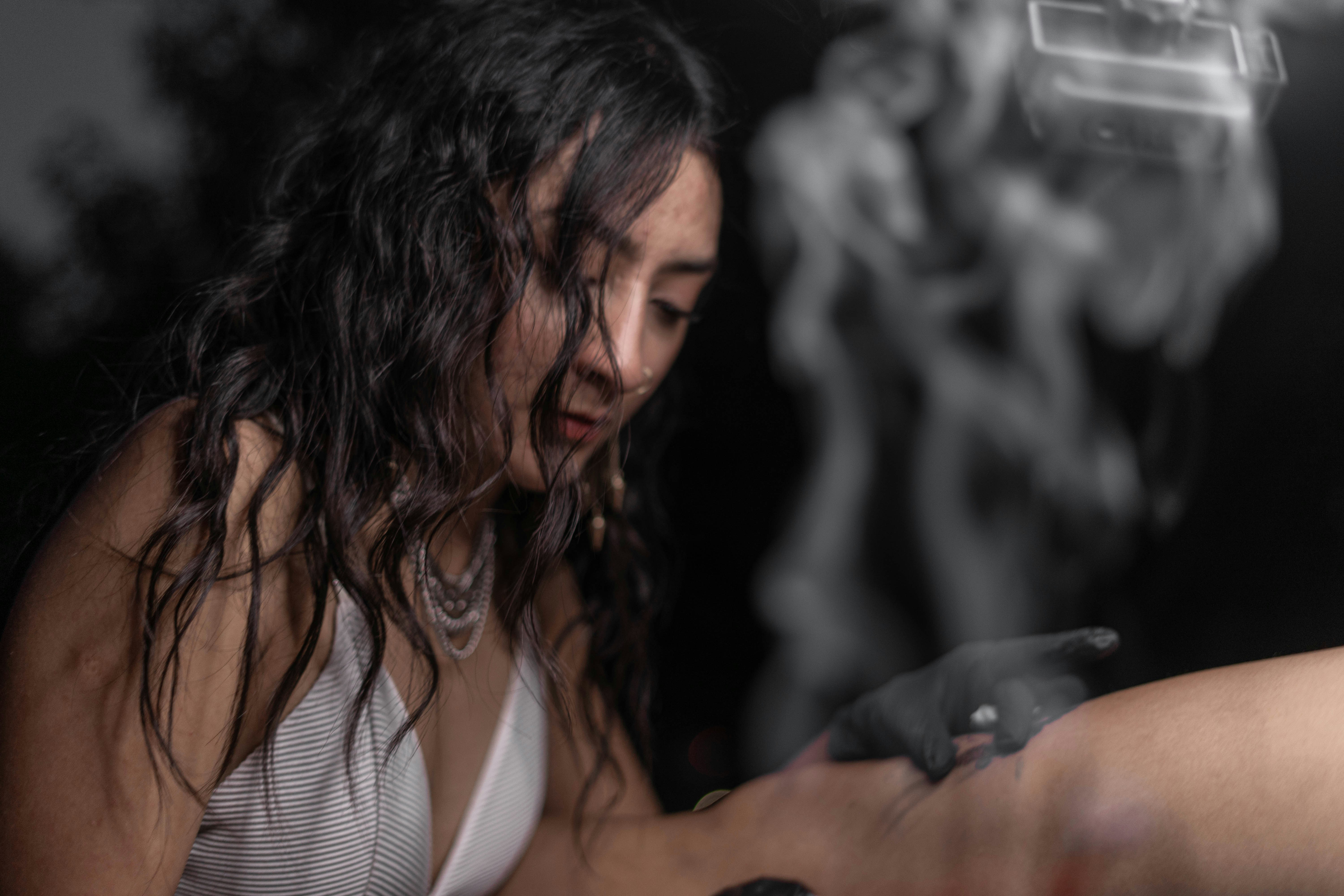 a woman smoking a cigarette in a white tank top
