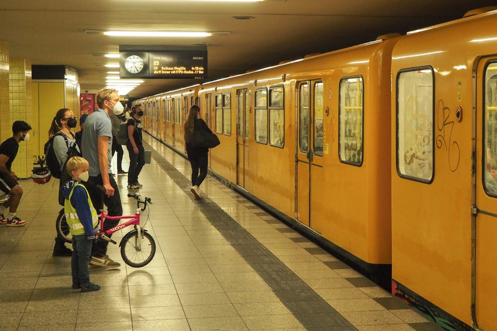 a group of people standing next to a yellow train