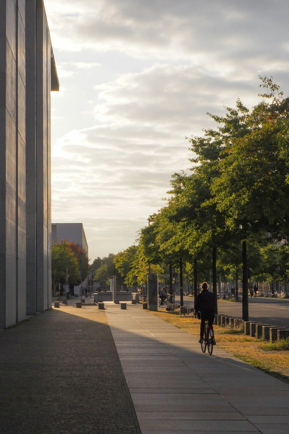 a man riding a bike down a sidewalk next to a tall building