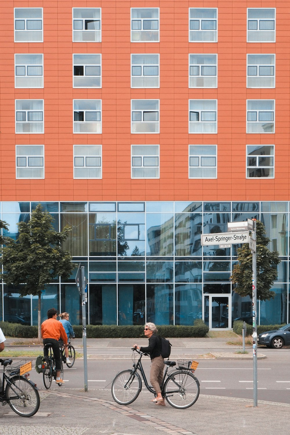 a group of people riding bikes down a street next to a tall building