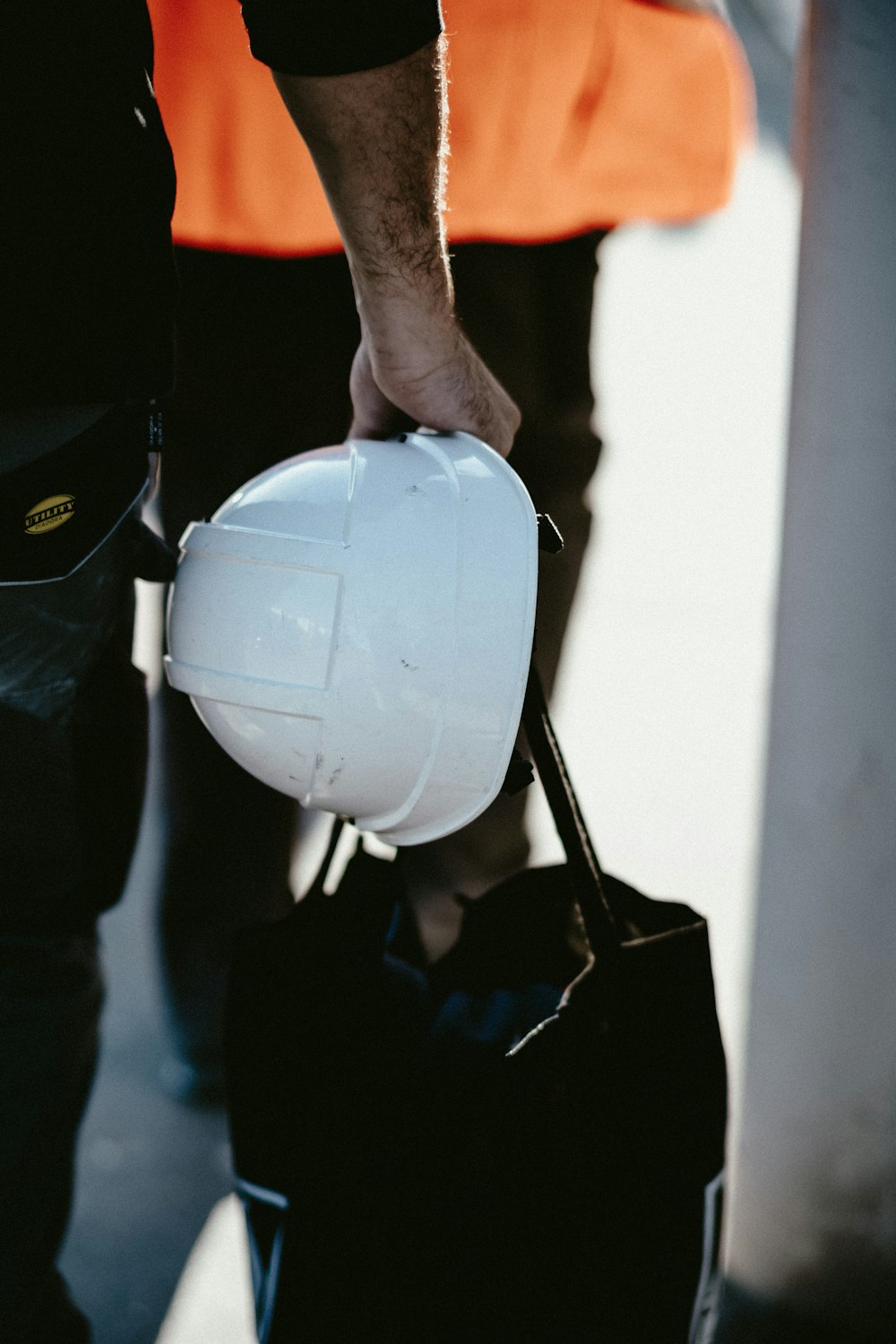 a man holding a white hard hat and a black bag
