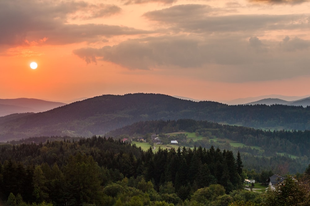 the sun is setting over the mountains in the distance