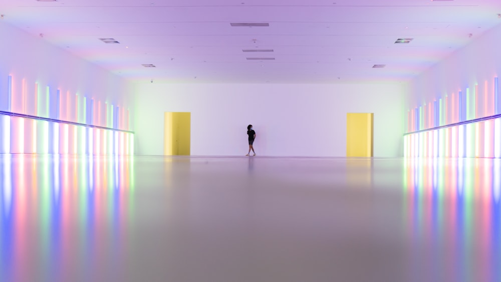 uma pessoa em pé em uma sala grande com luzes coloridas