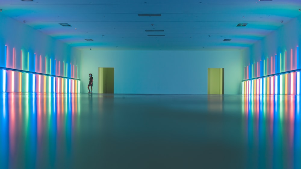 a person standing in a large room with neon lights