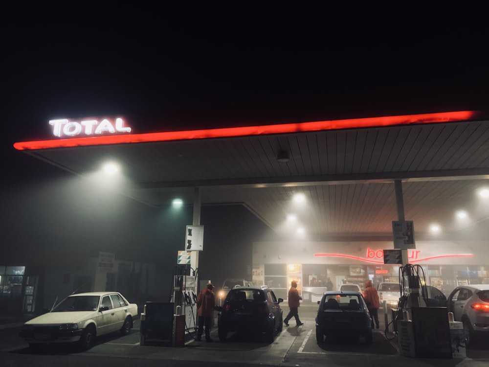 a gas station at night with cars parked in front of it