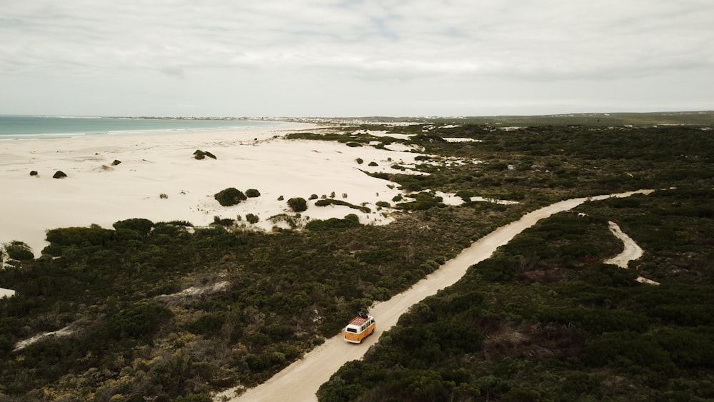 an aerial view of a car driving on a dirt road