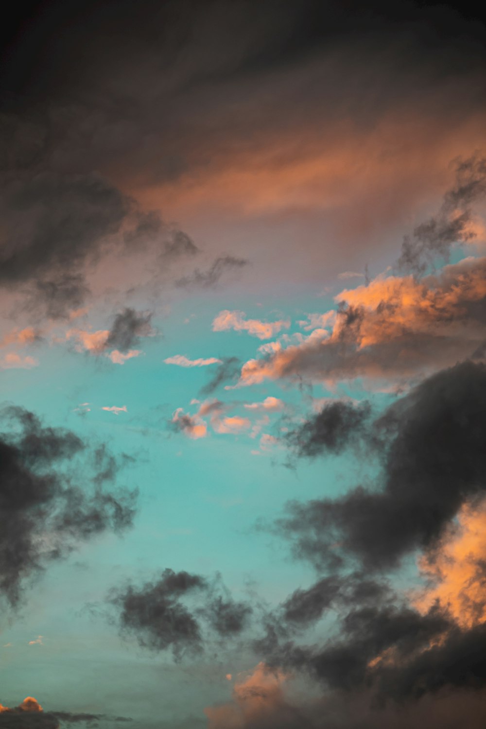 a plane flying through a cloudy sky at sunset