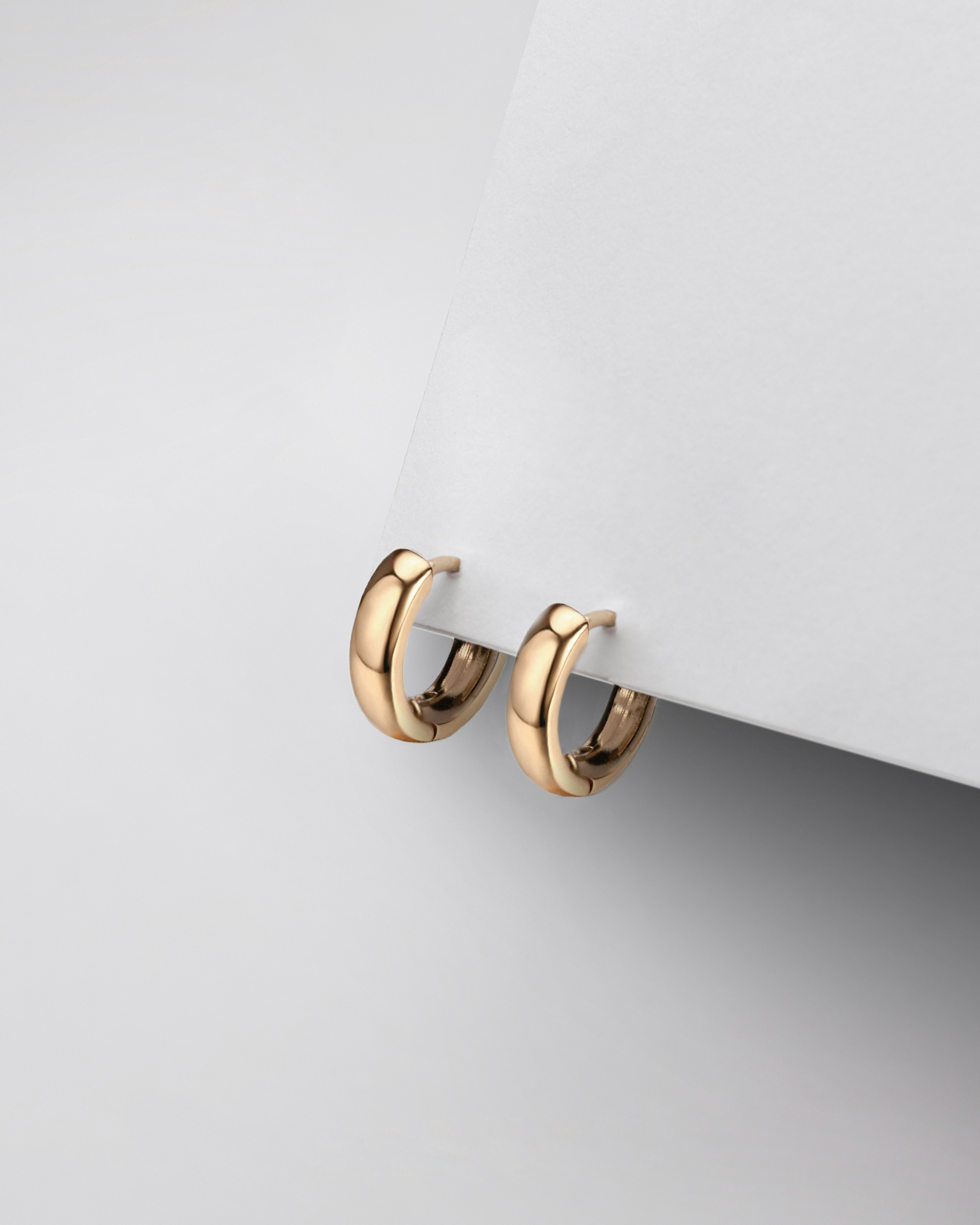 a pair of gold earrings on a white surface
