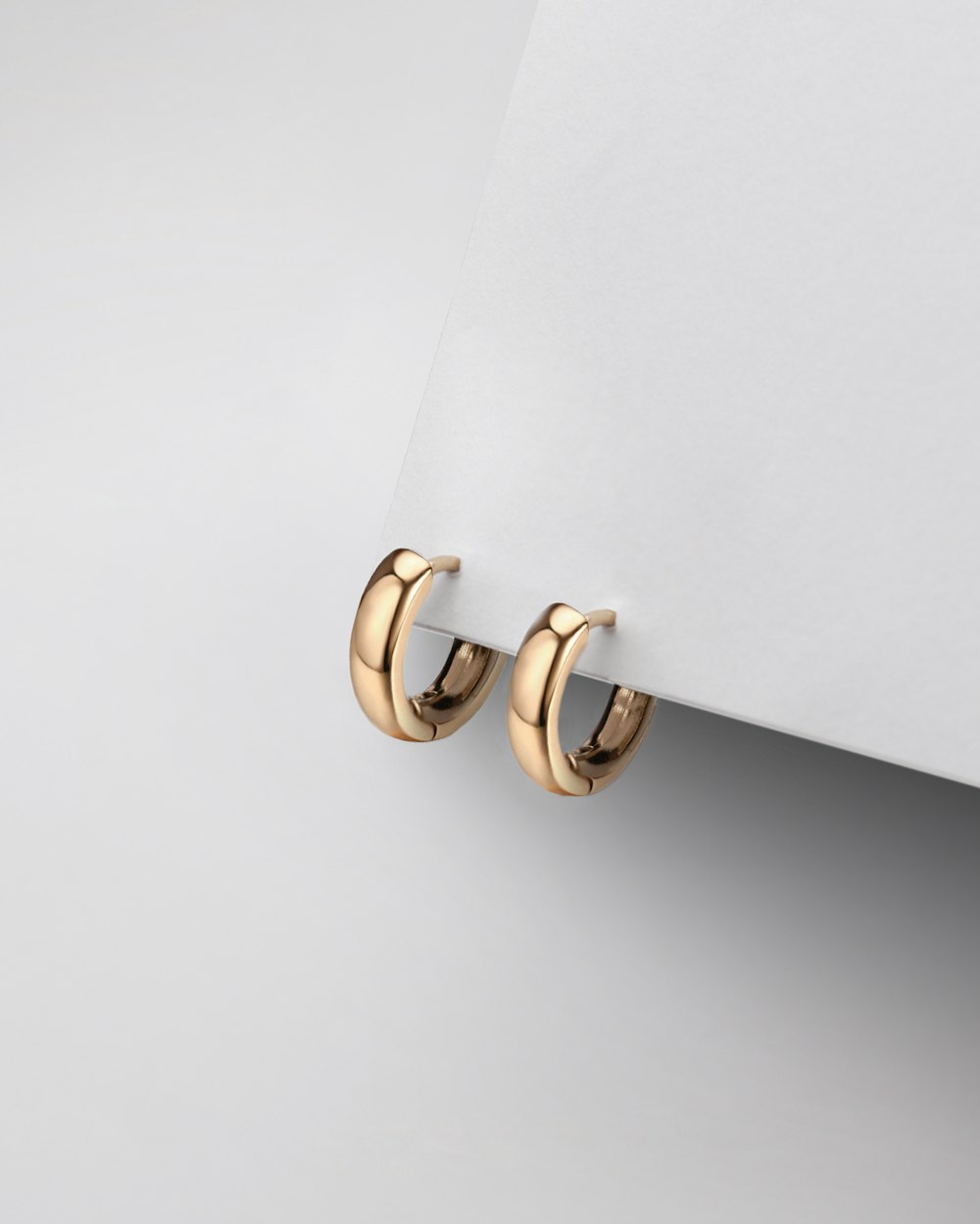 a pair of gold earrings on a white surface