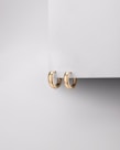 Elegant gold hoop earrings displayed on a minimalist white stand