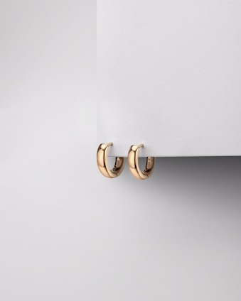 Pair of minimalist gold earrings displayed on a marble slab