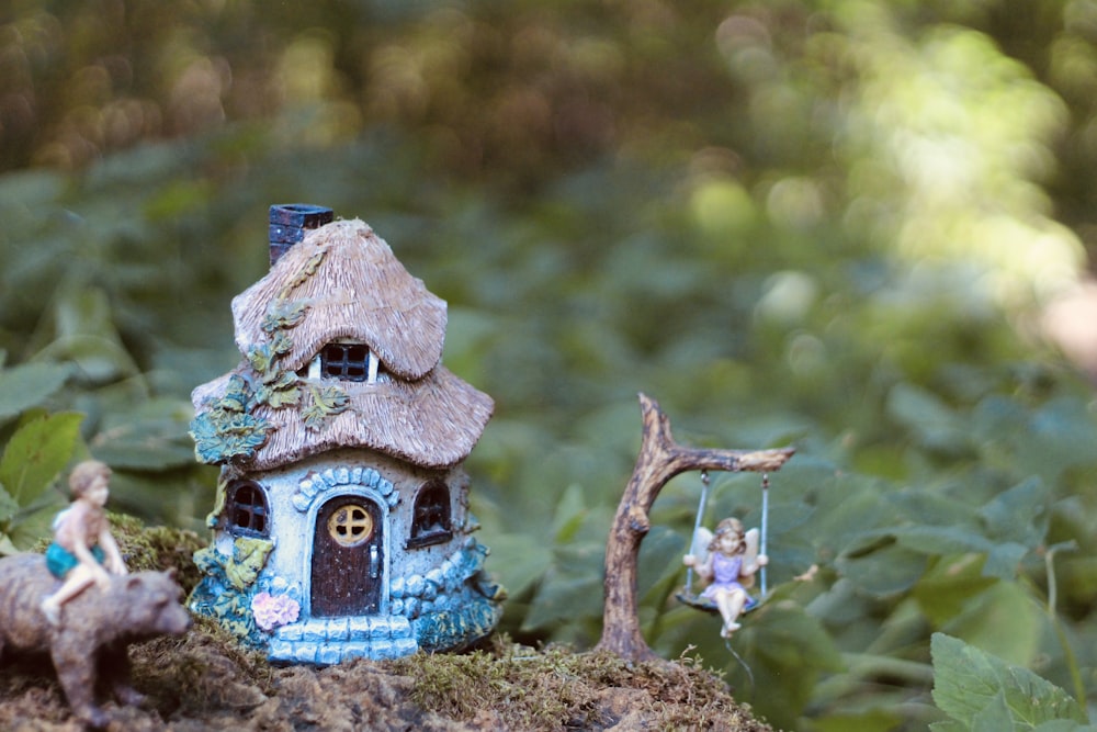 uma pequena casa azul com uma garotinha sobre ele