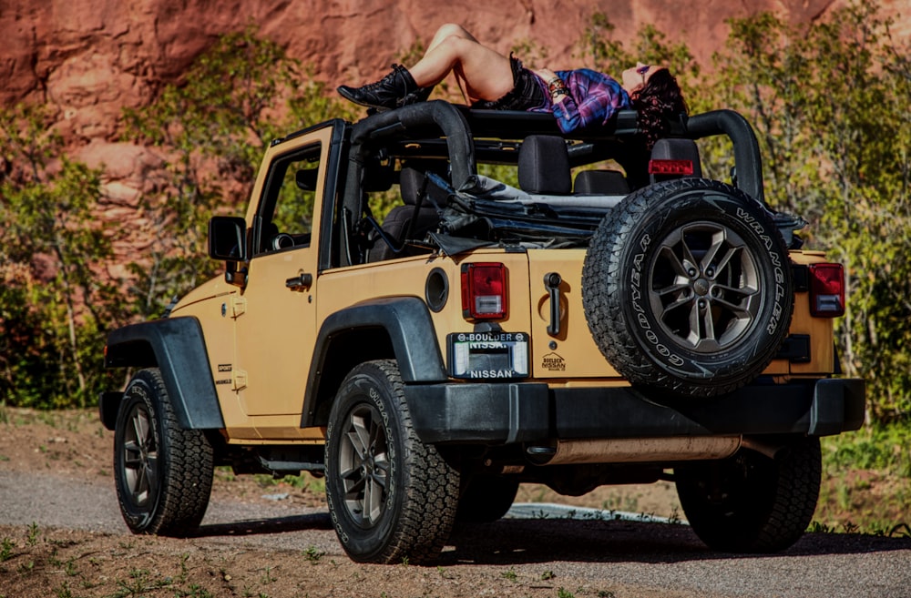 a woman laying on top of a yellow jeep