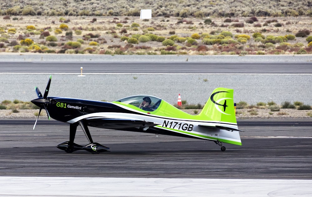 a small green and white airplane on a runway