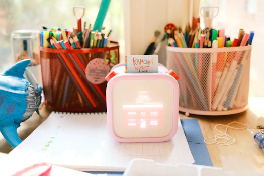 a pink alarm clock sitting on top of a desk