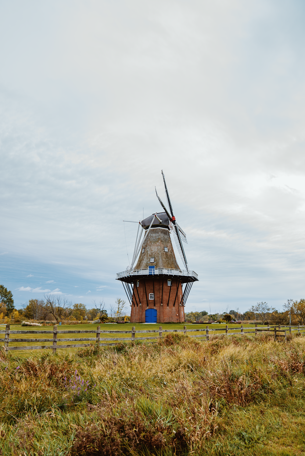 um moinho de vento em um campo com uma cerca em torno dele
