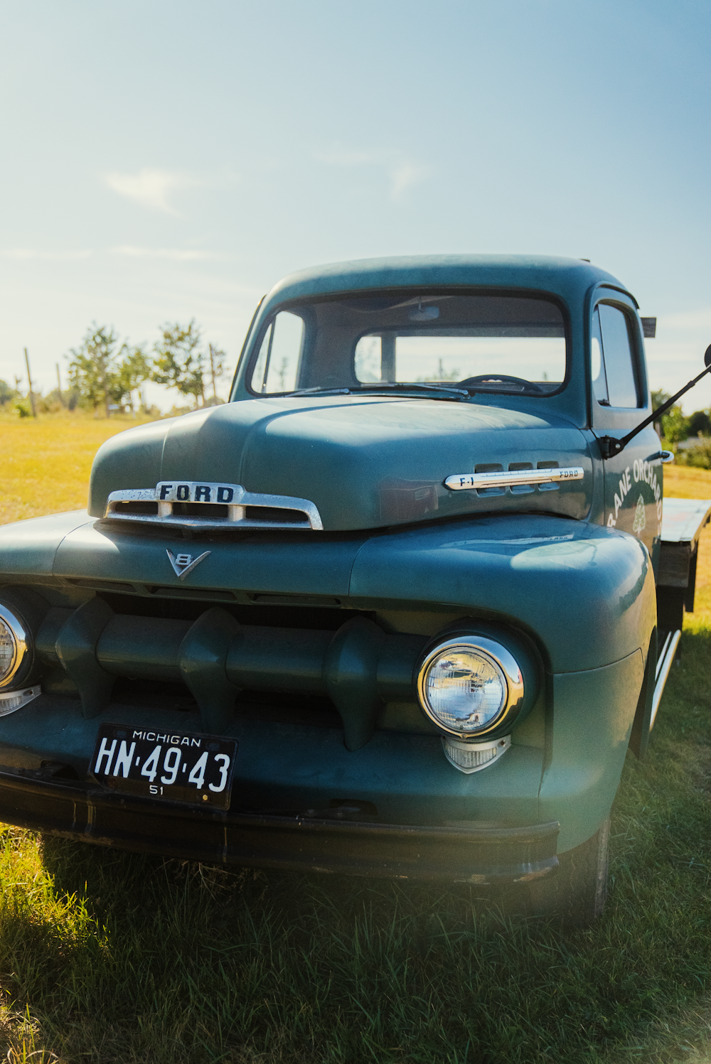an old green truck parked in a grassy field