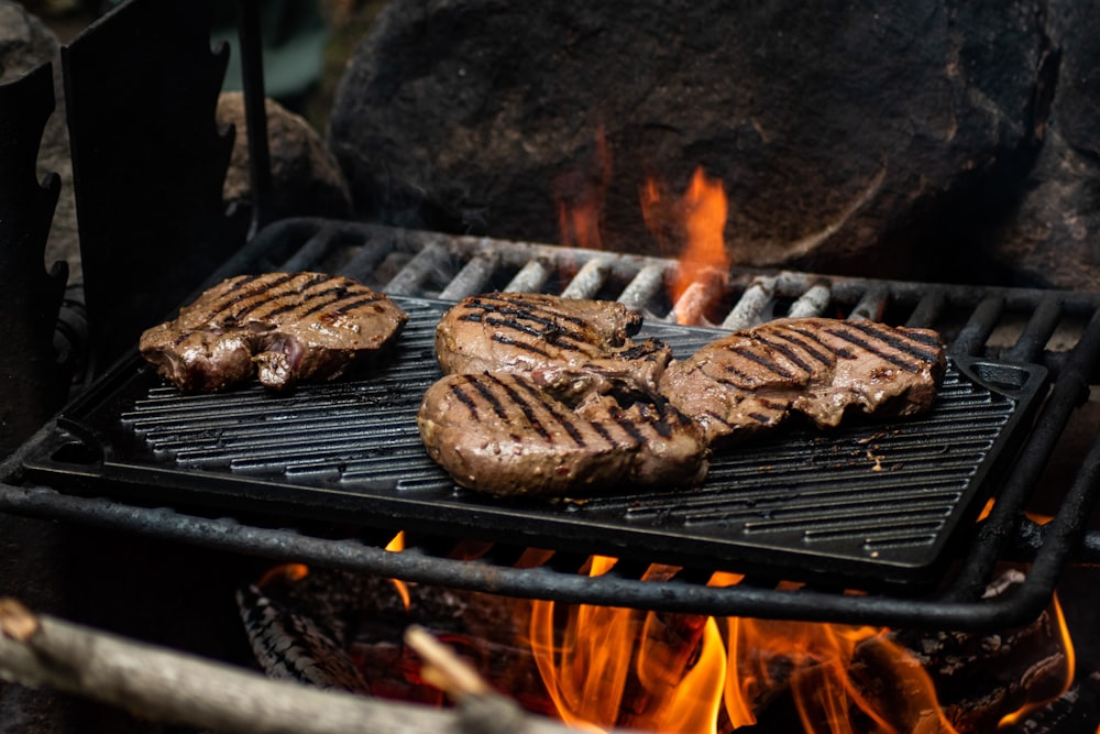 hamburgers and hamburger patties cooking on a grill