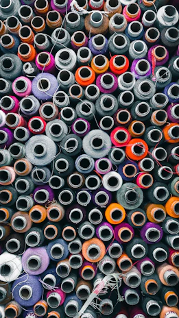 Close-up of colorful filament spools arranged in a gradient from cyan to purple.