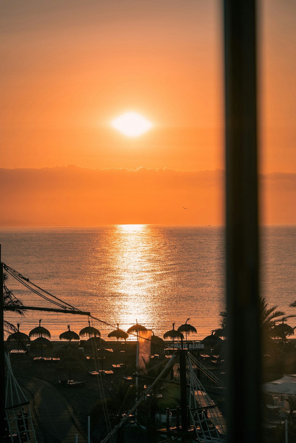 the sun is setting over the ocean with umbrellas