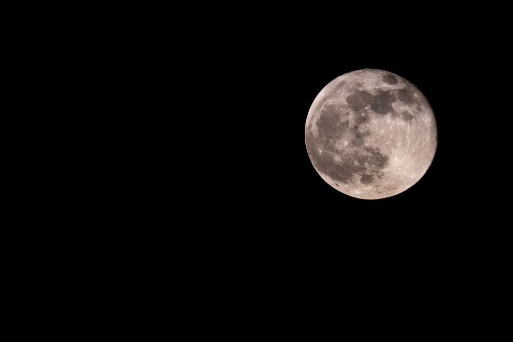 a plane flying in the sky with a full moon in the background