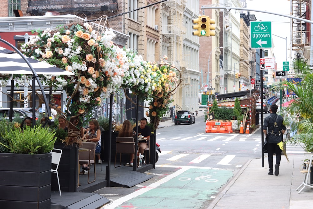 a street scene with people sitting at tables on the sidewalk