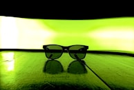 A cinematic shot of a luxury eyewear collaboration piece resting on an elegant mirrored surface.