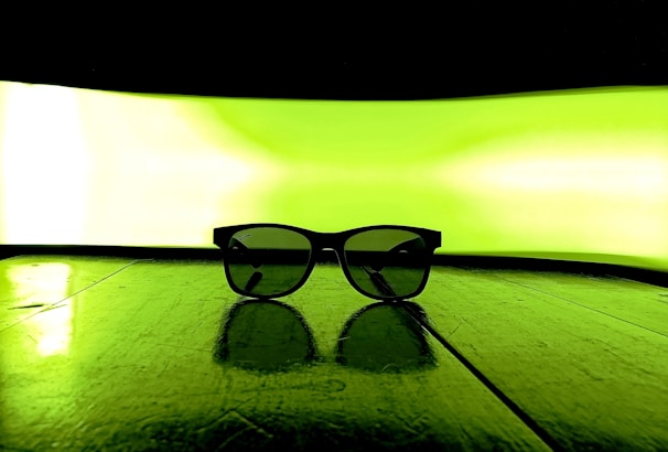 Minimalist arrangement of luxury men's sunglasses with gold accents on a smooth olive green background