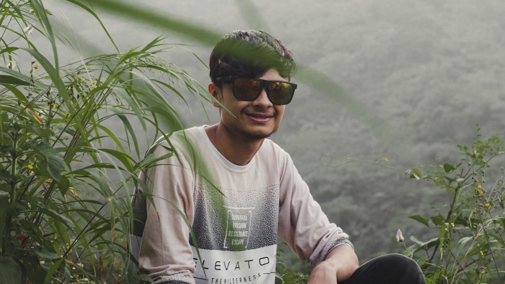 a man wearing a helmet and sunglasses sitting on a rock