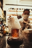 A bartender pouring a smoky whiskey cocktail into a chilled glass with ice cubes.