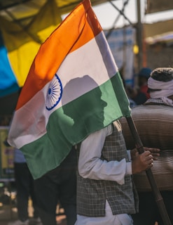 a man carrying a large indian flag on a street