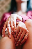 Close-up of hands resting on knees in a meditative pose, with soft focus on a calming background.