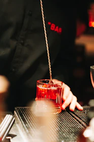 a person holding a glass of red liquid
