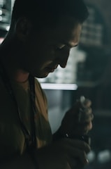 A hand holding improvised self-defense tools in a dimly lit room.