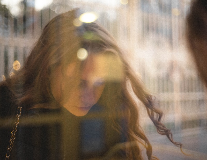 A woman’s face seen through window reflections and blurred lights