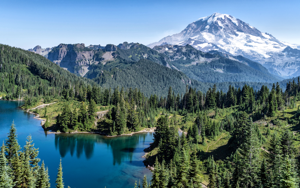 a mountain range with a lake surrounded by trees