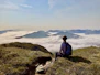 a woman sitting on top of a lush green hillside